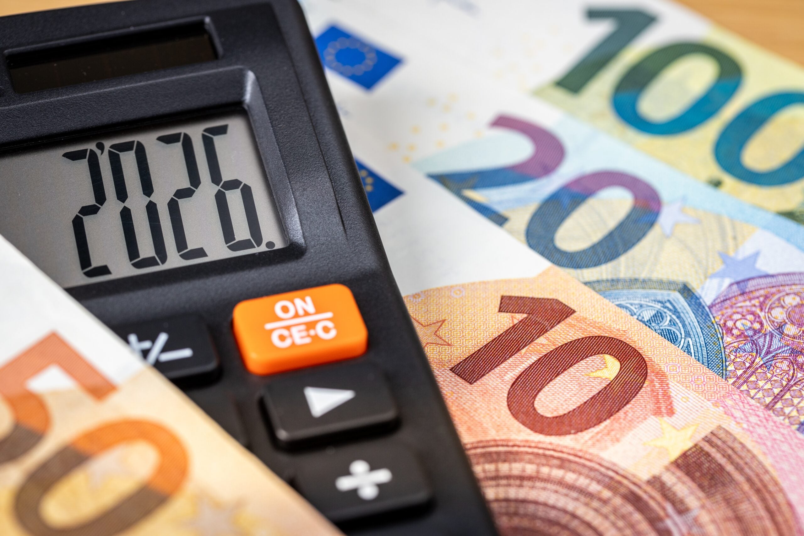 Kalkulator s prikazano letnico 2026 leži na evrskih bankovcih različnih vrednosti.